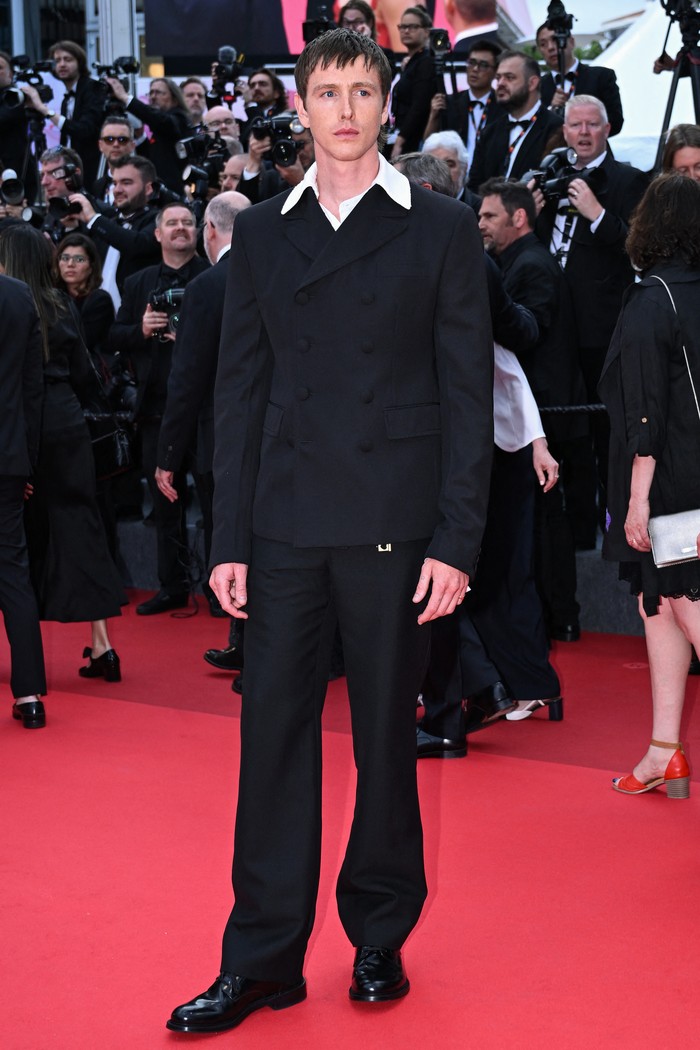 Harris Dickinson hadiri pemutaran film Urchin (16/5) dalam look terinspirasi koleksi Prada Fall/Winter 2016. Aktor Inggris itu layering garbadine jacket bekerah putih dengan poplin shirt serta panama trousers warna hitam. Ornamen keychain yang tersemat pada ikat pinggang beri sentuhan menarik pada gaya klasiknya/ Foto: Dok. Prada AFP via Getty Images/BERTRAND GUAY