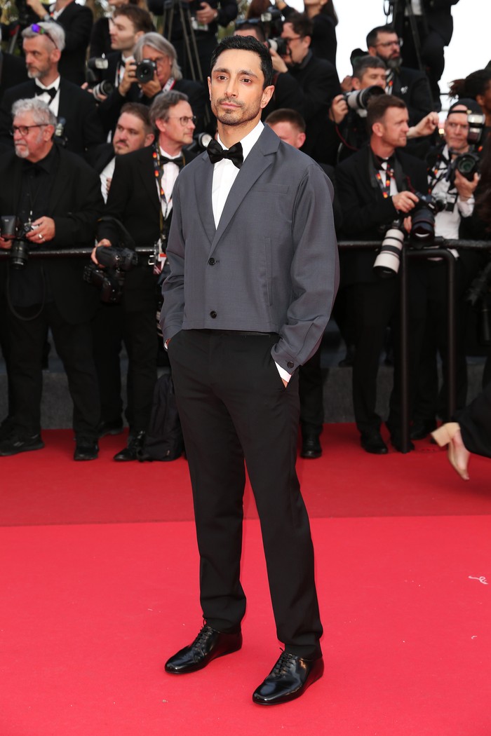 Penampilan klasik dengan twist modern ditampilkan Riz Ahmed saat menyaksikan The Phoenician Scheme di Cannes 2025 (18/5). Mengenakan busana Prada, setelan jas dengan bow tie yang biasanya menggabungkan jaket hitam formal diberi sentuhan kontemporer lewat perpaduan single-breasted blazer potongan pendek/ Foto: Dok. Prada/Getty Images/Gisela Schober