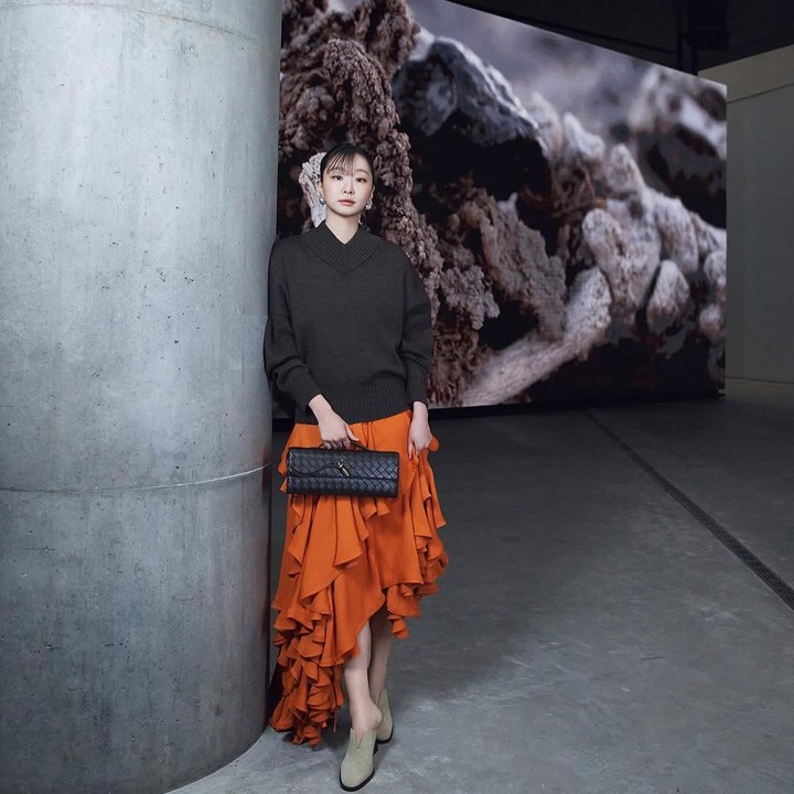 <p>Kemudian untuk tampilan lainnya, Kim Dami mengenakan <em>asymmetric ruffle long skirt</em> oranye dan atasan <em>knit</em> berwarna cokelat tua. (Foto: Instagram @d_a___m_i)</p>