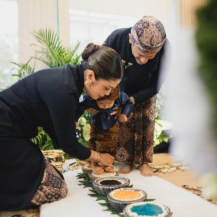 <p>Istri Nadiem, Franka Franklin, membagikan potret acara tedak siren anak bungsunya di media sosial. Dalam acara ini terlihat keluarga Nadiem kompak mengenakan pakaian adat Jawa berwarna serba hitam. (Foto: Instagram @frankamakarim)</p>