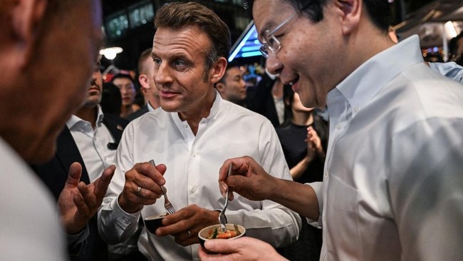 Macron Pamer Diajak Jajanan Lokal oleh PM Singapura Presiden Prancis Emmanuel Macron mengunggah momen mencicipi kudapan lokal di hari perdana kunjungannya di Singapura pada Jumat (30/5).