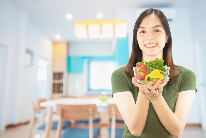 Happy lady holding kichen stuff over copy space background - people home made food preparation concept