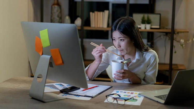 Ilustrasi wanita bekerja A young woman is working late at home and eating instant noodles for dinner