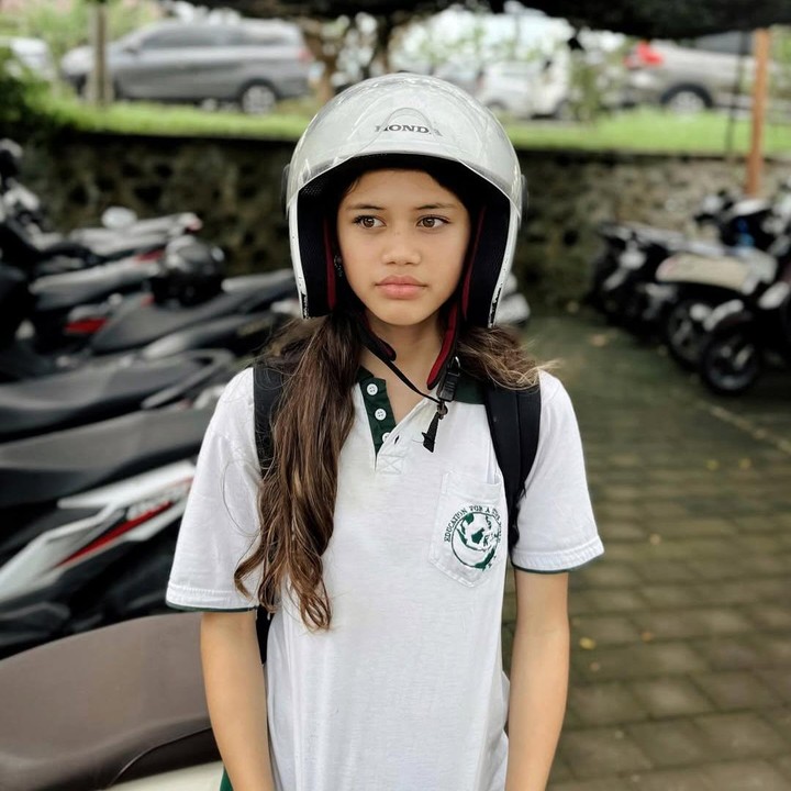 <p>Dalam unggahan ini, Andrew membagikan potret sang putri yang mengenakan helm putih sambil mengenakan baju sekolah. Foto ini diambil sebelum Sarah duduk di kursi motor yang dikendarai ayahnya. (Foto: Instagram @andrew.white._)</p>