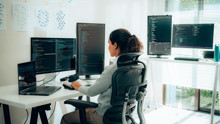 rear view of Hispanic woman Programmer Writing Code on Dual Monitors for Tech Projects