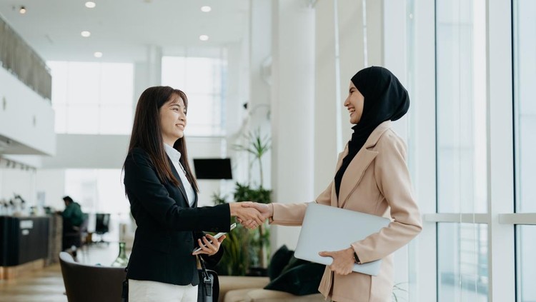 Two Asian businesswomen shake hands after a successful meeting