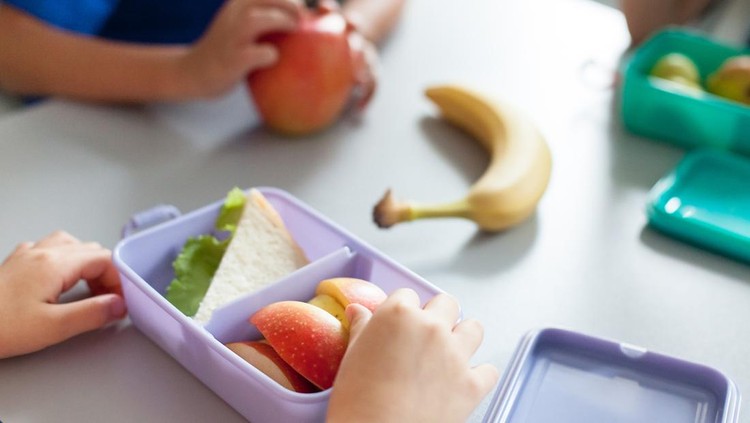 School kids eating healthy food from packed lunch boxes. Children sit at table in cafeteria. Pupils have vegetarian breakfast in canteen. Back to school concept. Lifestyle moment in elementary college