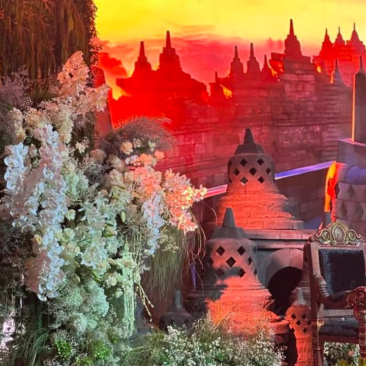 <p>Nuansa Jawa klasik semakin terasa di acara ngunduh mantu ini dengan dibangunnya minatur candi di area pelaminan, Bunda. Miniatur candi dan gambar candi-candi dengan pemandangan matahari tenggelam berada tepat di belakang kursi orang tua dari kedua mempelai. (Foto: Instagram @suryodecor)</p>