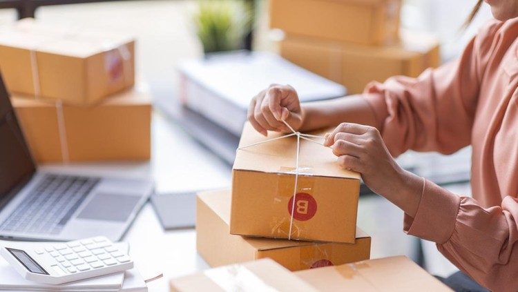 Ilustrasi bisnis pemula SME Online seller Young Asian woman working on laptop and box checking online order, check goods stock delivery package shipping postal. Asian woman startup SME small business at home office