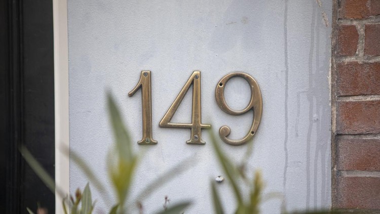 Metal house number sign on the wall outside a residential building in the city of Amsterdam