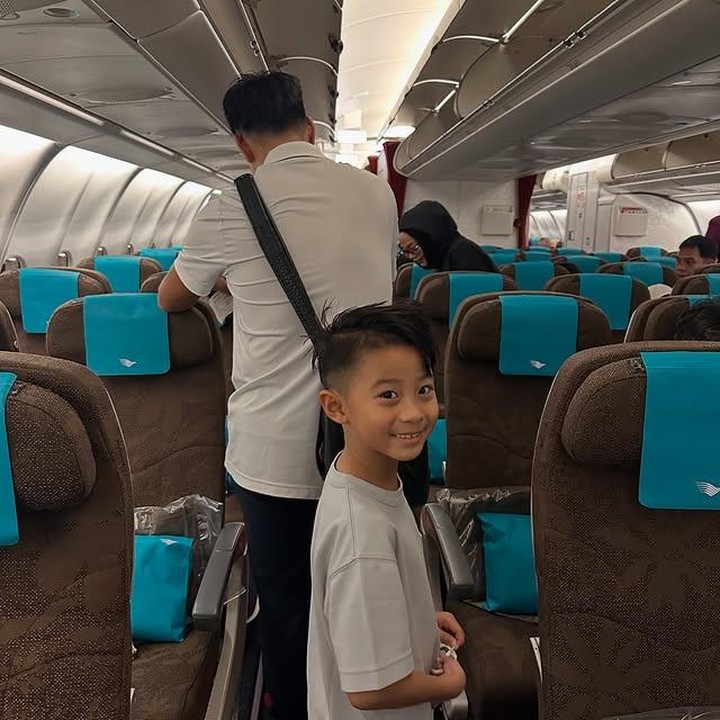 <p>Sang anak, Xavier Young Min Ha tampak terlihat di pesawat sambil tersenyum manis. Gayanya yang ceria seolah ikut menularkan semangat untuk memulai kehidupan baru di Australia. (Foto: dok. instagram@riniyulianti)</p>