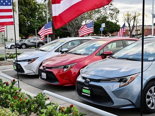 US flags fly outside a car dealership in Alhambra, California, on March 27, 2025. Automakers were battered on March 27 as stock markets fell on both sides of the Atlantic after US President Donald Trump announced significant tariffs on imported vehic