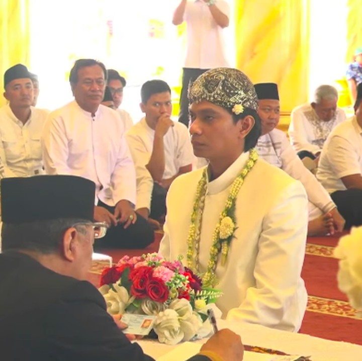 <p>Momen akad nikah pasangan ini dibagikan melalui siaran langsung di kanal YouTue milik Mega. Pada momen itu, Dio yang terlihat mengenakan busana pengantin lengkap berwarna putih tengah bersiap mengucapkan ijab kabul di hadapan penghulu dan para saksi.&nbsp;(Foto: YouTube Megawati Smash Up)</p>