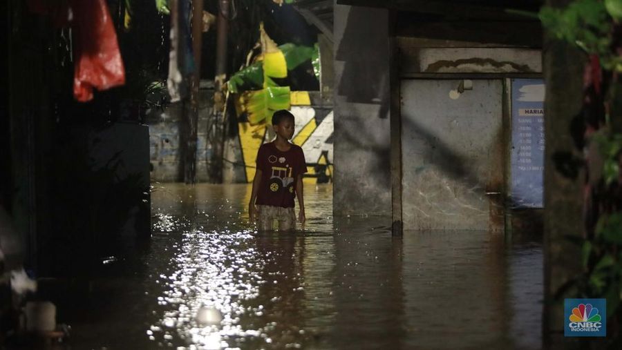 Sejumlah penduduk melintas di tengah banjir di RW 06 Jatipadang, Jakarta Selatan, (6/7/2025). (librosfullgratis.com/Muhammad Sabki)