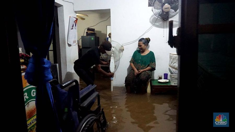 Sejumlah penduduk melintas di tengah banjir di RW 06 Jatipadang, Jakarta Selatan, (6/7/2025). (librosfullgratis.com/Muhammad Sabki)