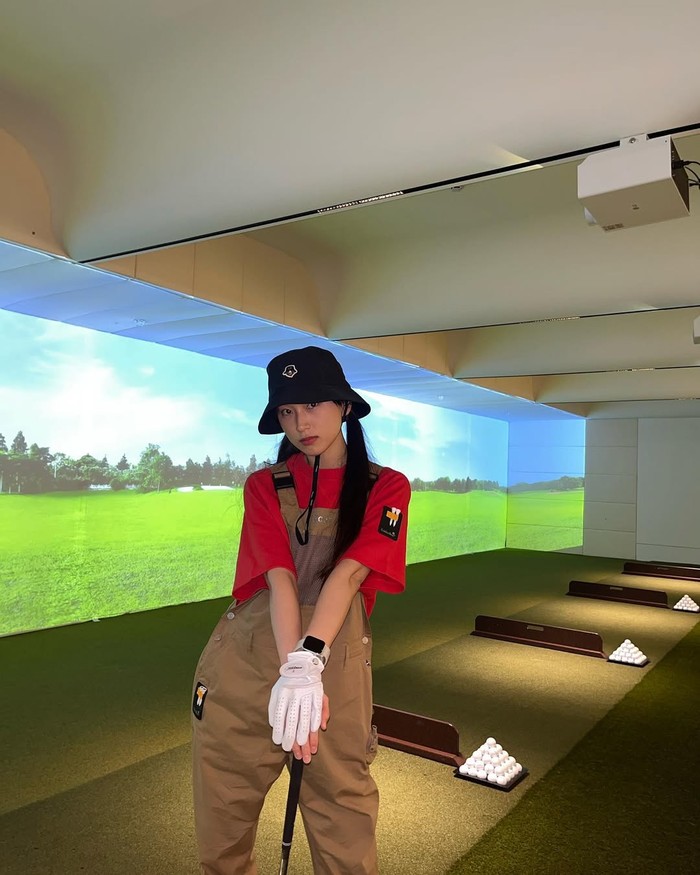 Hobi golf, perempuan kelahiran 1991 ini, bermain virtual golf dengan mengenakan kaus merah yang dipadukan overall cokelat dan bucket hat hitam untuk tampil modis/ Foto: Instagram.com/ryuniverse328