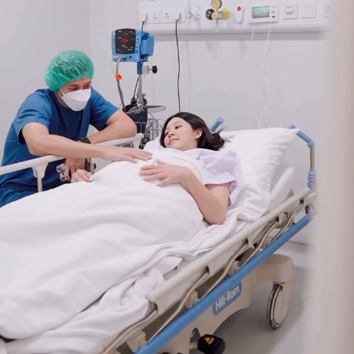 <p>Melalui unggahan di Instagram, Ribka membagikan momen persalinan pertamanya. Sebelum memasuki ruang bersalin, tampak Rian duduk menemani Ribka. Rian terlihat sedang mencoba menenangkan istrinya. (Foto: Instagram @ribkasugiarto)</p>
