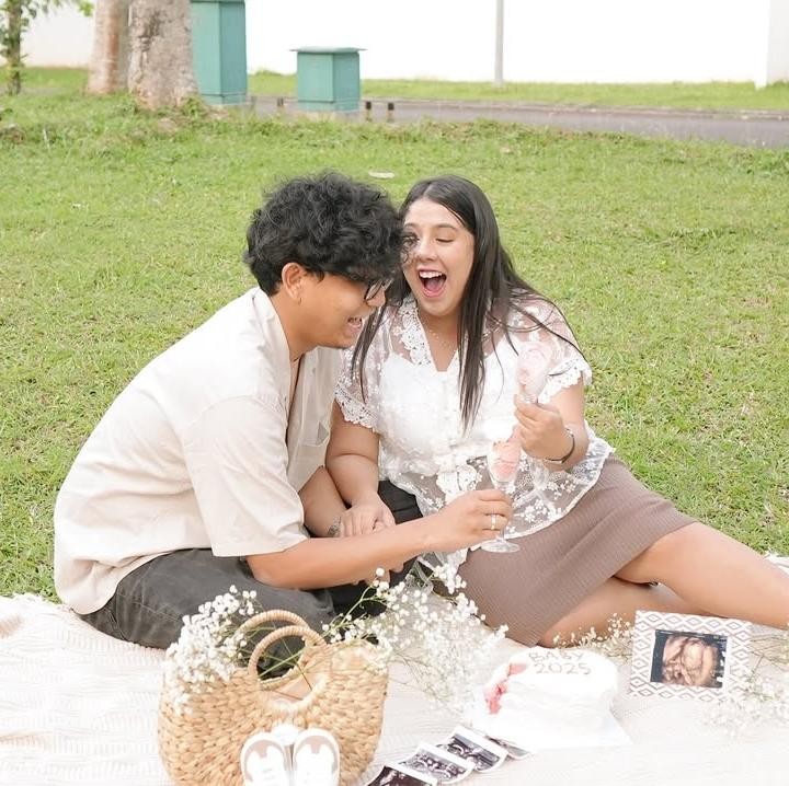 <p>Dalam gender reveal ini, Nessie dan sang suami kompak mengenakan baju berwarna putih. Keduanya lalu duduk rumput dengan alas kain putih dengan keranjang bunga dan foto USG calon bayi mereka. (Foto: Instagram @nessiejudge)</p>