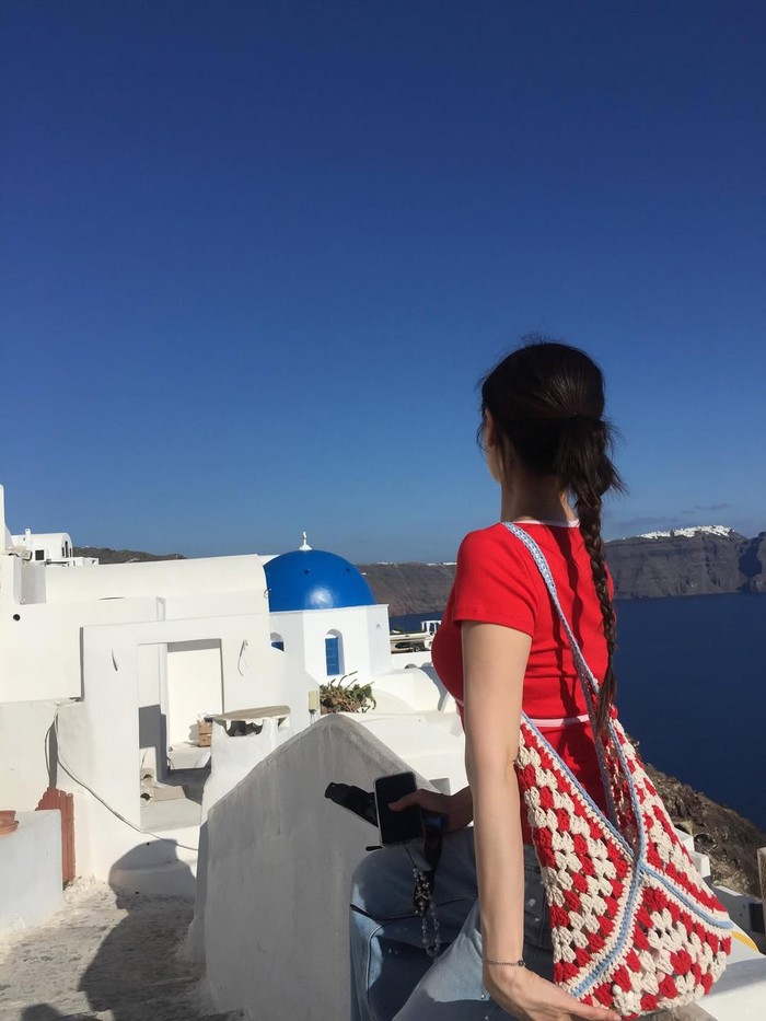Di salah satu fotonya, Jung So Min sedang duduk di pagar pembatas sambil menyaksikan kemegahan gereja kubah biru yang menjadi bangunan ikonik di Santorini serta menikmati kesegaran udara yang berhembus./ Foto: instagram.com/somin_jj