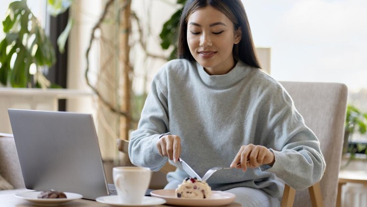 Ilustrasi makan makanan manis Cute asian girl eating tasty dessert while working at the cozy cafe. Remote working and education concept. Stock photo