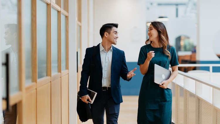 Image of two white collar workers having a discussion in modern office. Businessman and businesswoman discussing business strategy while walking in the corridor