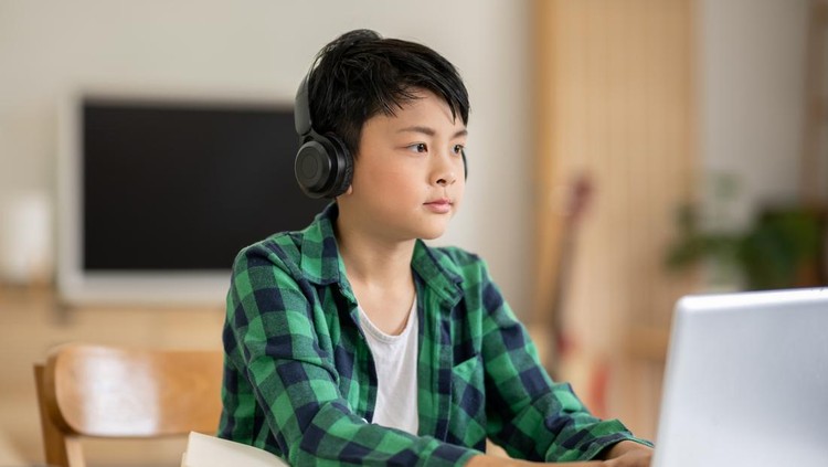 Ilustrasi gen alpha A boy is studying online intently on his laptop at home.