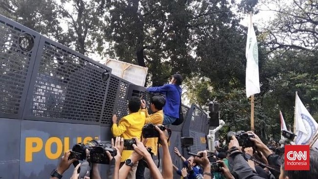 Massa BEM SI merusak spanduk imbauan yang dibawa oleh aparat kepolisian saat demo.