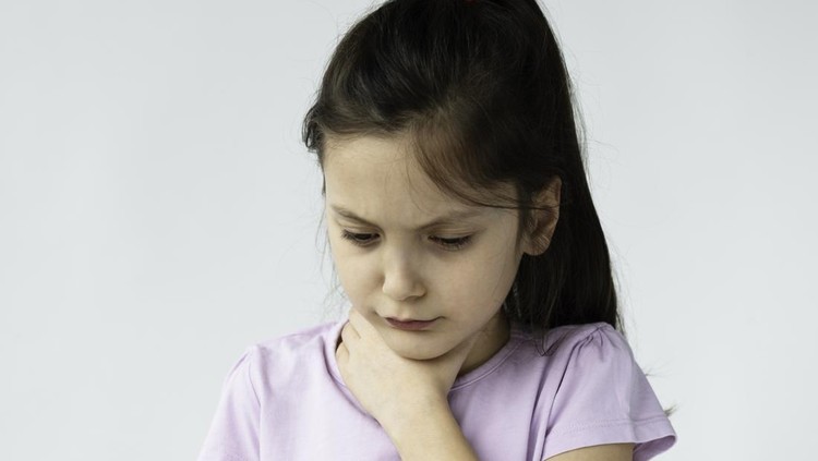 Little girl is holding her throat in pain in front of white background.