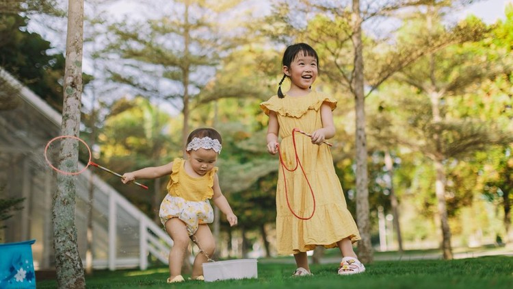 Ilustrasi anak Two Asian toddler girl are happily playing bubbles in a garden park.