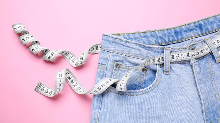 Jeans and measuring tape on pink background, top view