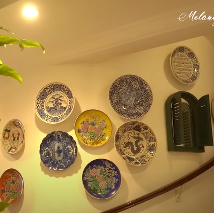 <p>Yuni Shara banyak menggunakan hiasan dinding dari piring dan guci yang bergaya <em>vintage</em>. Piring-piring digantung di dinding, sementara guci diletakkan di beberapa sudut ruangan. Yuni mengaku bahwa ia memang suka mengoleksi hiasan piring ini, Bunda. "Ini piring-piring kuno, aku tuh koleksi kayak keramik Cina. Iya aku (suka) yang <em>vintage</em>," ungkap Bunda dua anak ini. (Foto: YouTube Melaney Ricardo)</p>