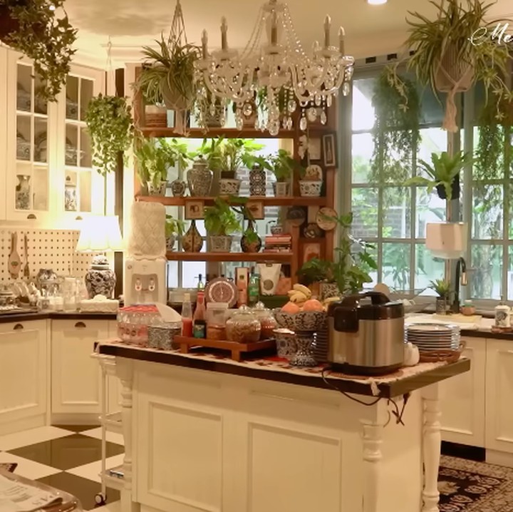 <p>Di area dapur, Yuni juga masih mengusung tema <em>aesthetic</em>. Ia banyak menaruh kolekasi gucinya di dapur ini, Bunda. Dapur masak Yuni ini banyak didominasi oleh warna putih dengan tanaman hijau menggantung di atap. (Foto: YouTube Melaney Ricardo)</p>