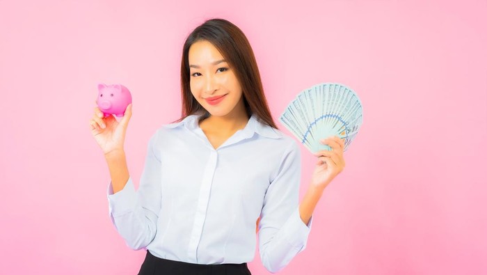 Portrait beautiful young asian woman with a lot of cash and money on pink background