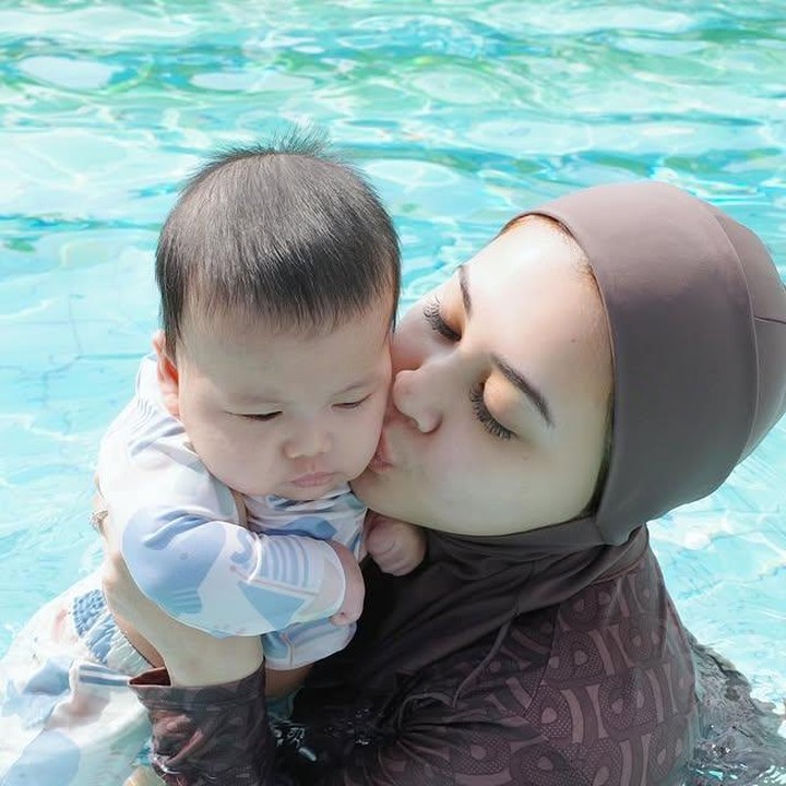 <p>Dalam beberapa potretnya, Bunda Kesha pun juga terlihat percaya diri saat menemani Danish berenang. Kesha memastikan bayinya nyaman dan aman berada di pelukannya saat di kolam renang. (Foto: Instagram @kesharatuliu05)</p>