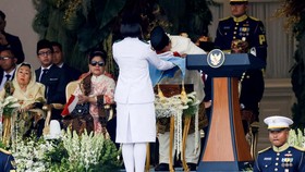 Presiden Prabowo Subianto (kanan) mencium duplikat Bendera Merah Putih saat diserahkan kepada Paskibraka pembawa baki Bianca Alessia Christabella untuk dikibarkan dalam Upacara Peringatan Detik-Detik Proklamasi Kemerdekaan ke-80 Republik Indonesia di
