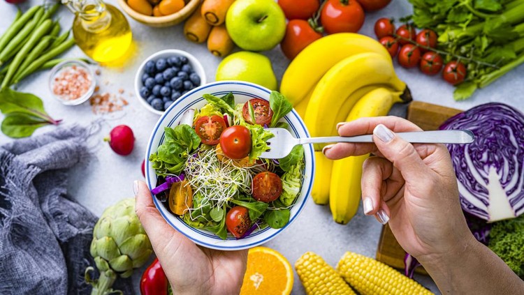 Ilustrasi diet buah Woman eating fresh rainbow colored salad. Multicolored fruits and vegetables background. Healthy eating and dieting concept. High resolution 42Mp studio digital capture taken with SONY A7rII and Zeiss Batis 40mm F2.0 CF lens