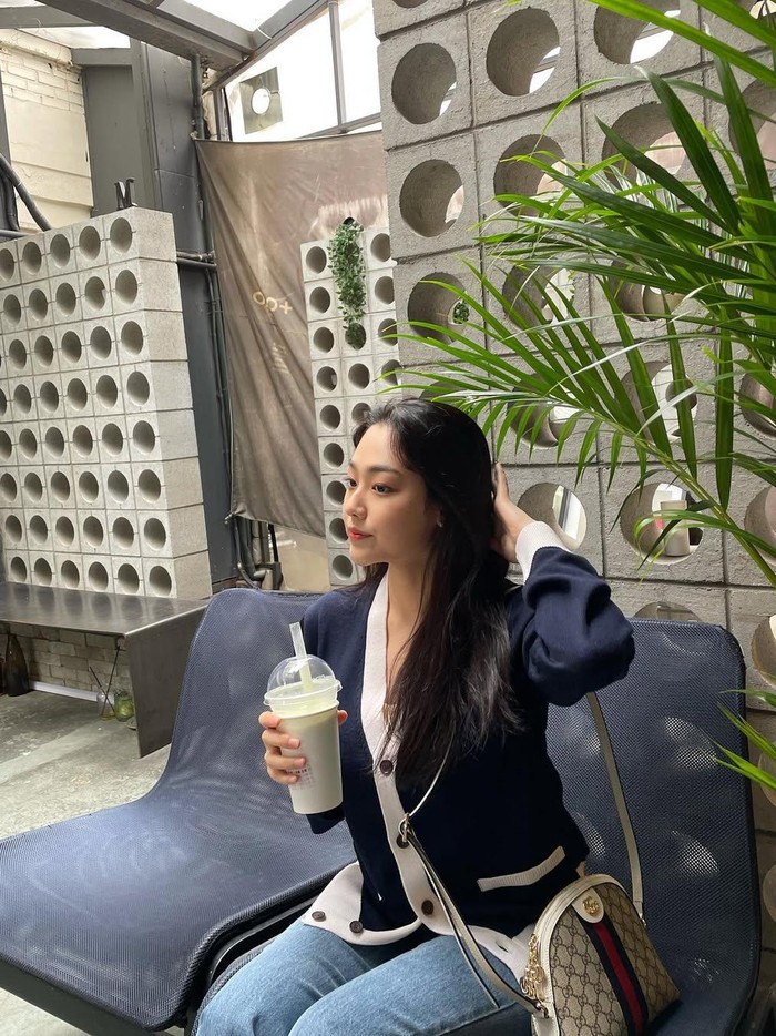 Hangout cantik di kafe, ia terlihat santai dengan cardigan navy yang mempunyai aksen putih, memadukannya dengan celana jeans membuatnya makin stylish dan comfy./ Foto: Instagram.com/happiness_o