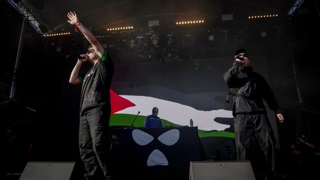 Northern Ireland hip-hop band Kneecap perform on stage in front of a Palestinian flag on a screen during a concert at the Rock en Seine music festival in Saint-Cloud, near Paris, on August 24, 2025. (Photo by Guillaume BAPTISTE / AFP)