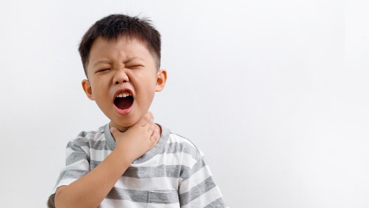 Ilustrasi anak menelan benda asing Young little Asian boy holding his neck, experiencing a sore throat problem.