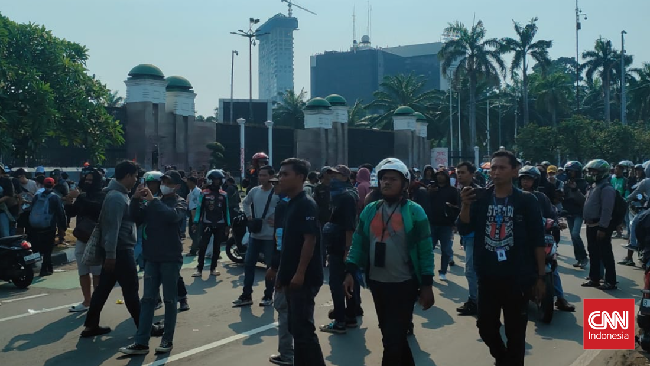 Ratusan orang berkumpul di Jalan Pangeran Jayakarta, Bekasi, dengan suara ledakan petasan dan asap dari benda dibakar. Polisi dan tentara berjaga di lokasi.