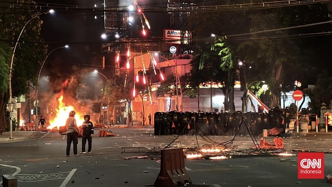 Situasi di pusat kota Surabaya malam ini mencekam karena bentrokan antara demonstran dan polisi. Protes ini terkait tewasnya pengemudi ojek online di Jakarta.
