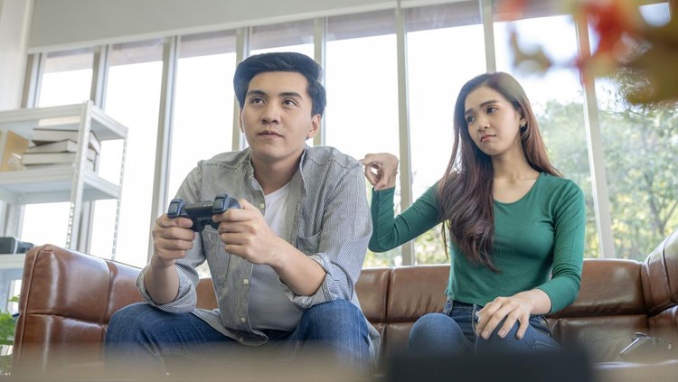Ilustrasi man child atau pasangan The young man plays games, ignoring his girlfriend