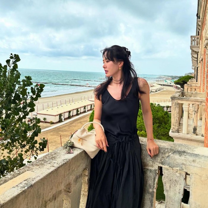 Pada salah satu potret, Son Ye Jin memancarkan gaya klasik dan elegan. Ia mengenakan dress hitam polos dan hand bag.