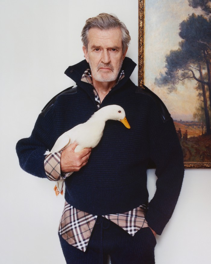 Rupert Everett, aktor film My Best Friend's Wedding, bergabung dalam pemotretan, Beauties. Sambil memegang angsa yang kini jadi salah satu ikon Burberry, Everett lebih santai tapi modis dalam balutan sweater hitam dengan lining khas Burberry check/ Foto: Courtesy of Burberry