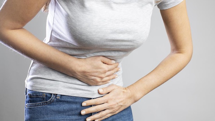 Young woman having painful stomach ache&period; Chronic gastritis&period; Stomach or menstrual cramps&period; Abdomen bloating concept&period;