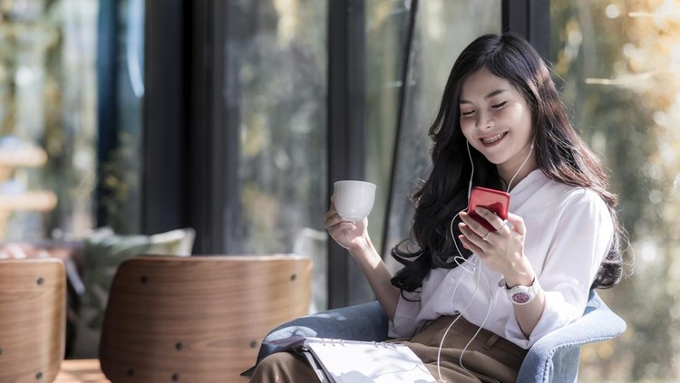 Ilustrasi cafe atau kafe Shot of a beautiful young asian woman holding cup of coffee and listening music from her phone in the coffee shop