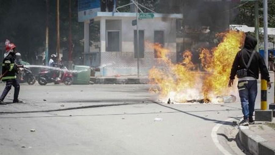 A firefighter extinguishes a blaze set alight by university students protesting the parliaments plan to buy 65 SUVs for lawmakers in Dili, East Timor, on September 16, 2025. East Timor police fired tear gas on September 16 at protesters railing for the second day against a plan to buy new official cars for lawmakers, which became the latest flashpoint in one of the poorest nations in Southeast Asia. (Photo by VALENTINO DARIELL DE SOUSA / AFP)