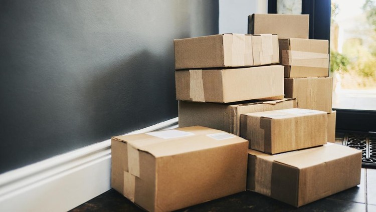 Ilustrasi paket belanja online A neatly stacked arrangement of brown cardboard boxes near a doorway, showcasing a recent delivery.
