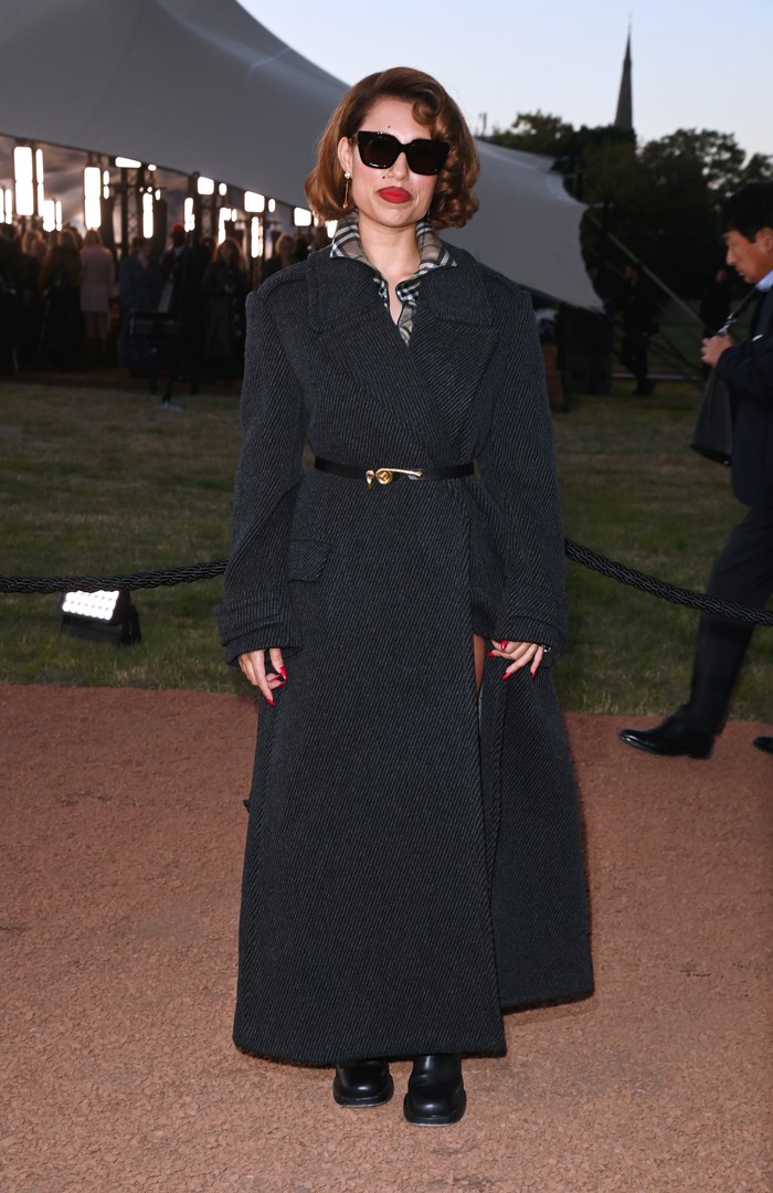 Di luar panggung, Raye berpenampilan ekstra elegan. Coat dress wool dengan kerah bermotif check tak hanya jadi aksen yang menambah pesona gaya, tapi juga dipermanis ikat pinggang kecil dengan hardware emas yang mencolok di antara rona gelap outfit tersebut/ Foto: Courtesy of Burberry/ Dave Benett/Dave Benett