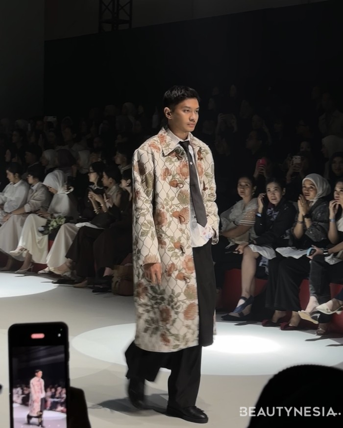 Koleksi lainnya, kemeja berwarna biru cerah dan celana hitam yang sederhana, tapi terlihat menawan dengan long coat bermotif bunga. (Foto: Rini Apriliani/Beautynesia)